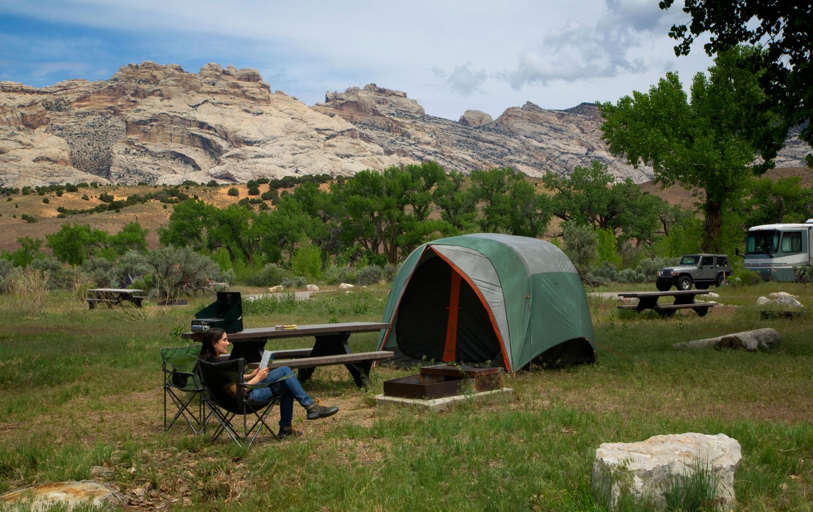 A camper in front of her tent at Green River Campground, with Split Mountain in view