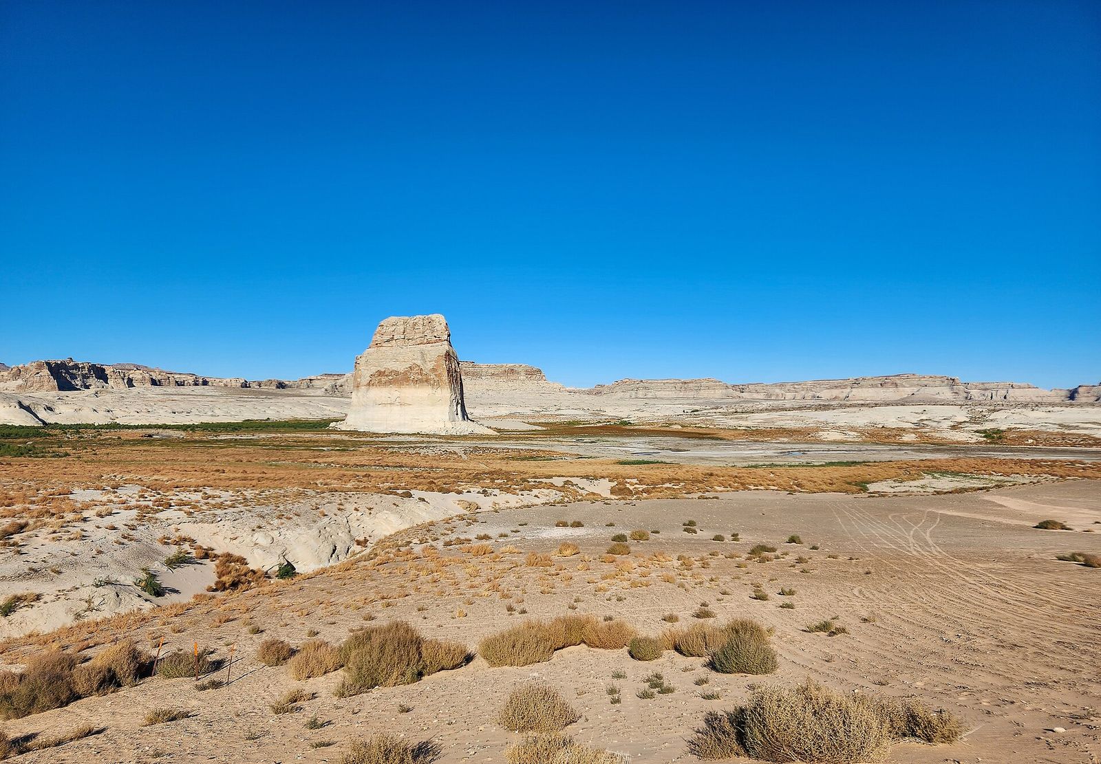Lone Rock rising above the sandy flats and tire tracks of the Lone Rock Beach camping area, with the low 2022 lake level exposing the shore