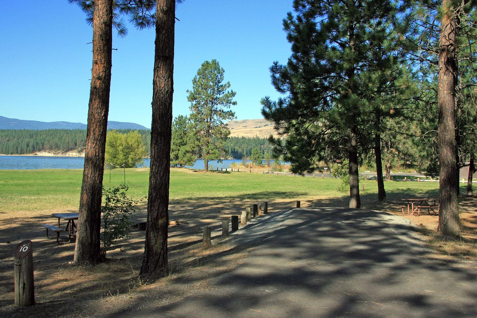A regular site has a paved parking space, picnic table, and fire pit